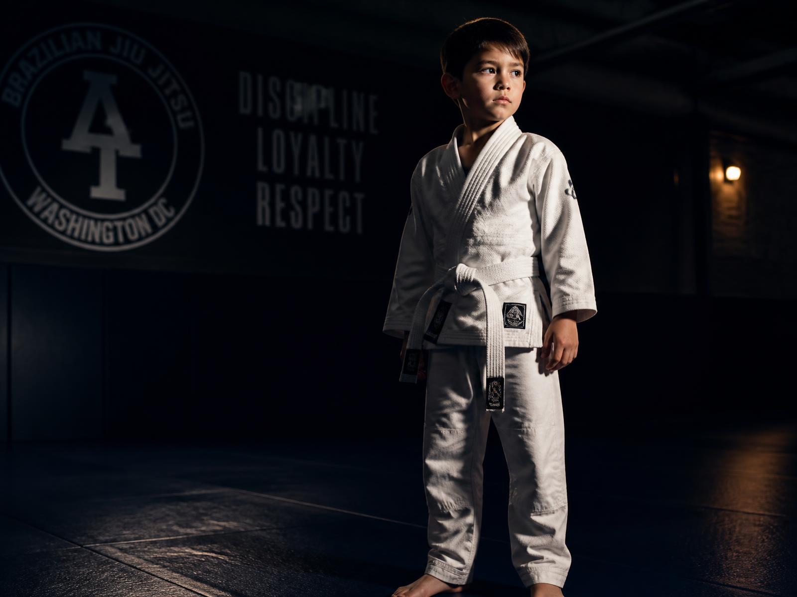 Young Brazilian jiu-jitsu student in a white gi standing on the mat at a San Diego gym